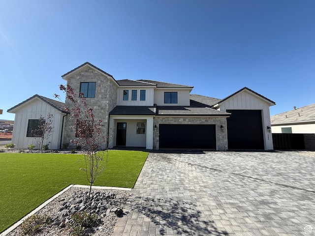 view of front of house with stone siding, decorative driveway, a front lawn, a garage, and board and batten siding