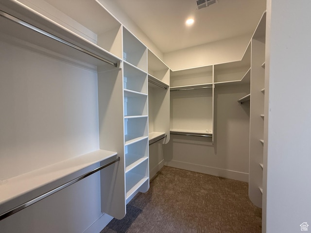walk in closet featuring dark carpet