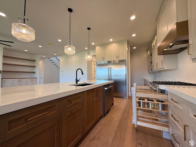 kitchen with appliances with stainless steel finishes, a sink, tasteful backsplash, recessed lighting, and light wood-style floors