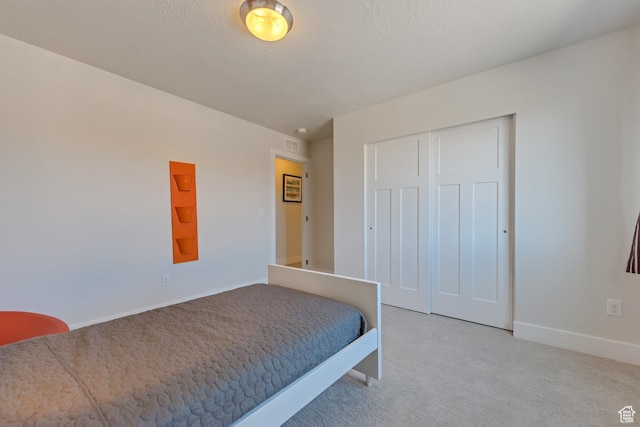 carpeted bedroom featuring baseboards and a closet