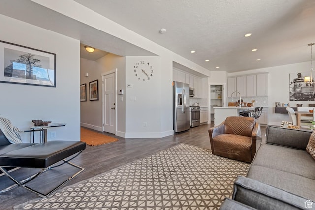 living area featuring dark wood finished floors, recessed lighting, a chandelier, and baseboards