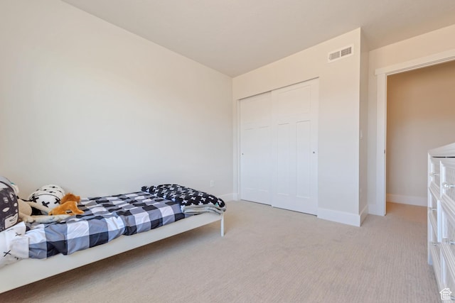 bedroom featuring light colored carpet, baseboards, and a closet