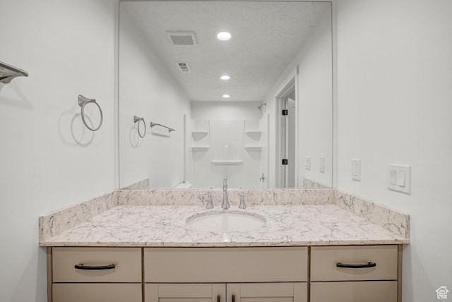full bathroom with recessed lighting, vanity, a shower, and a textured ceiling