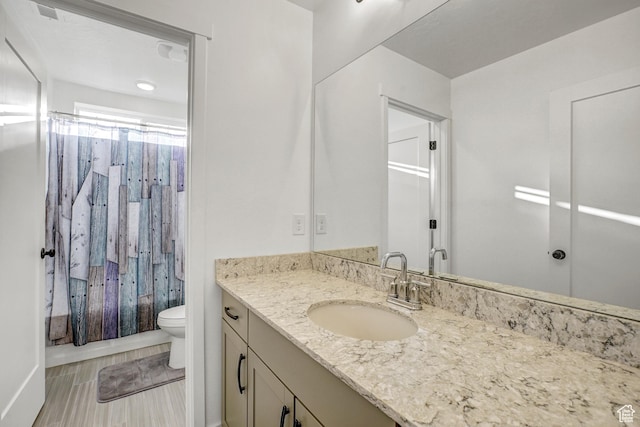full bathroom featuring toilet, vanity, and wood finished floors