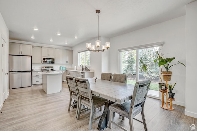 dining space featuring light wood-style floors, a chandelier, recessed lighting, and baseboards