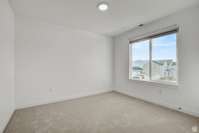 spare room with light carpet and baseboards