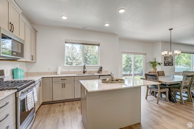 kitchen with stainless steel appliances, a sink, a chandelier, a center island, and light wood finished floors