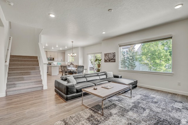 living area featuring stairway, recessed lighting, light wood-style flooring, a textured ceiling, and baseboards