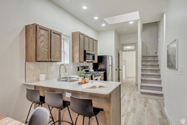 915 W 300 S, Salt Lake City, UT 84104 - kitchen with appliances with stainless steel finishes, a sink, a kitchen breakfast bar, light wood-type flooring, and recessed lighting