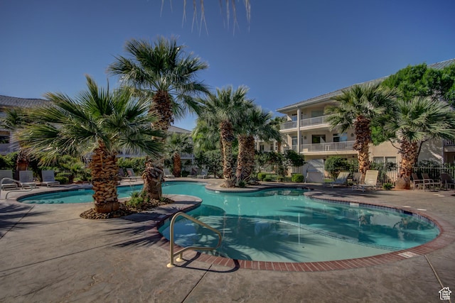 community pool with a patio and fence