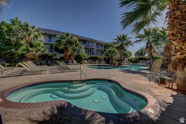 community pool with a community hot tub and a patio area