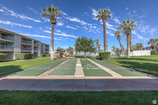 view of property's community featuring a lawn and shuffleboard
