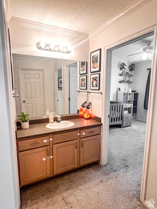 bathroom with ornamental molding, a ceiling fan, a textured ceiling, vanity, and carpet floors