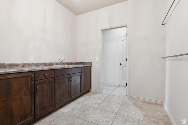 417 E Stonehedge Cir, Washington, UT 84780 - kitchen with dark brown cabinets, a sink, baseboards, and light tile patterned flooring