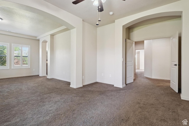 417 E Stonehedge Cir, Washington, UT 84780 - spare room featuring arched walkways, dark carpet, a ceiling fan, and baseboards
