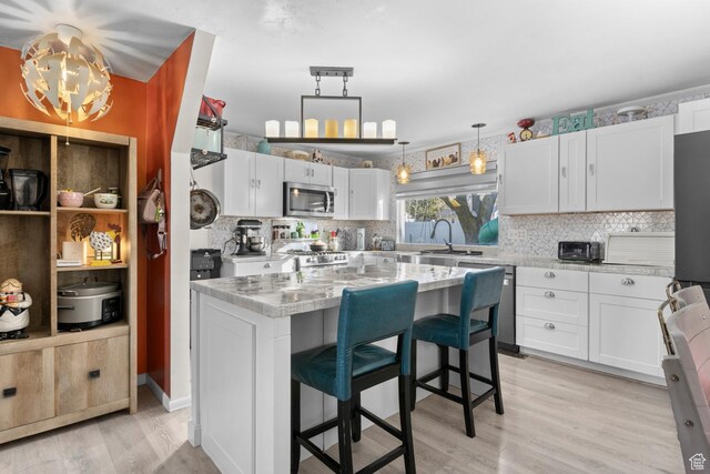 8521 W 3100 S, Magna, UT 84044 - kitchen with stainless steel appliances, tasteful backsplash, light wood-style floors, and white cabinetry
