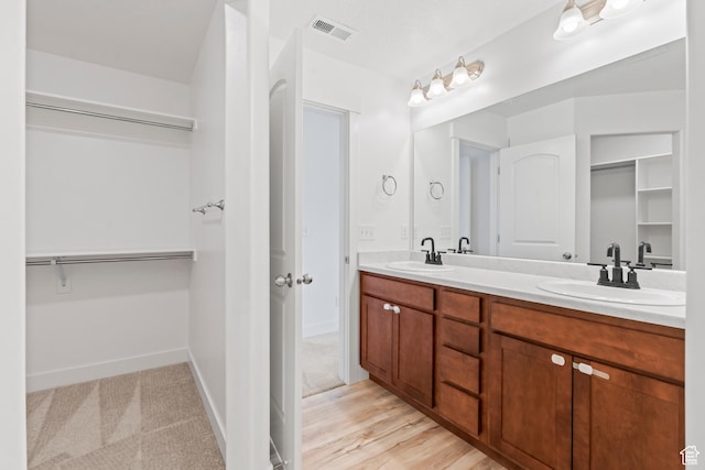 full bathroom with a spacious closet, double vanity, and baseboards