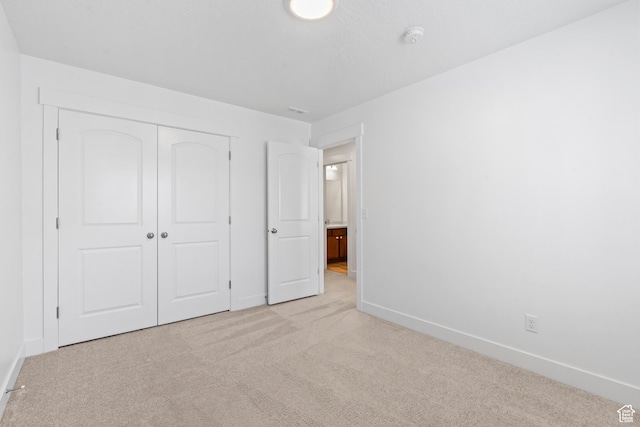 unfurnished bedroom with light colored carpet, baseboards, and a closet