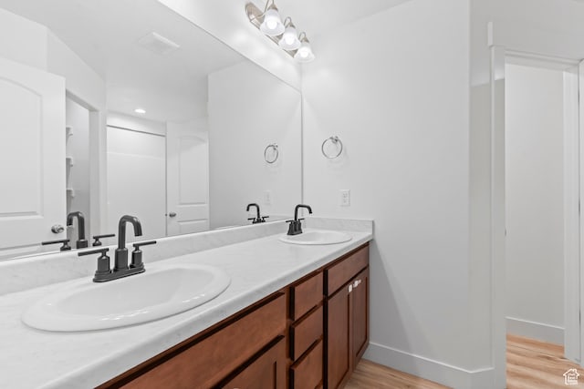 bathroom featuring wood finished floors, double vanity, and baseboards