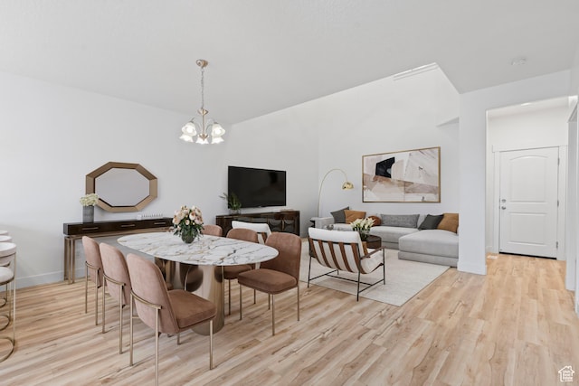 dining space with light wood-style flooring, a chandelier, and baseboards