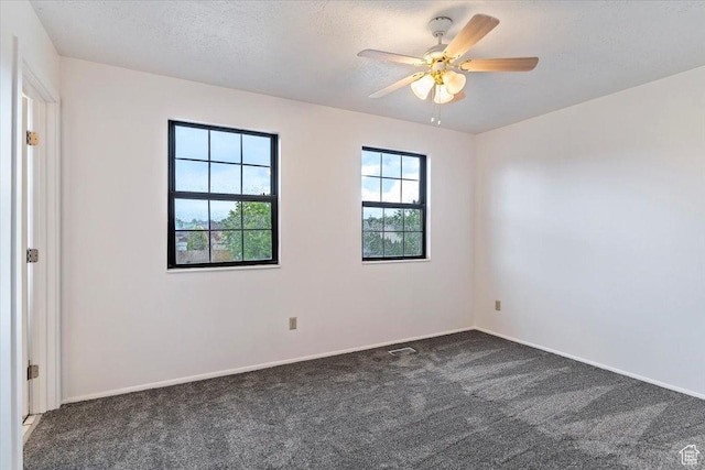 spare room with dark colored carpet, baseboards, and a ceiling fan