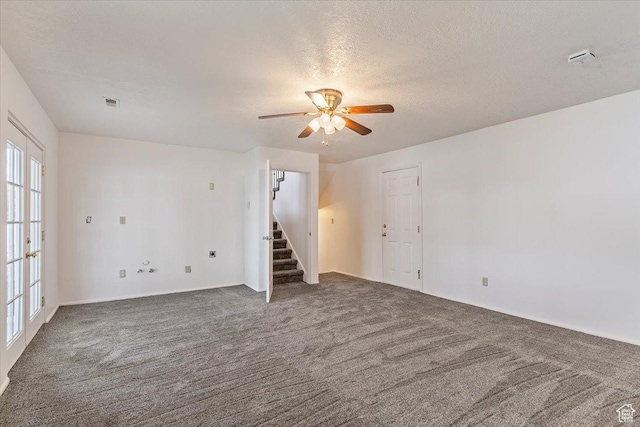 carpeted spare room with ceiling fan, stairway, and a textured ceiling