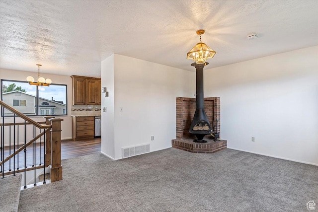 unfurnished living room featuring a chandelier, carpet floors, stairway, baseboards, and a textured ceiling