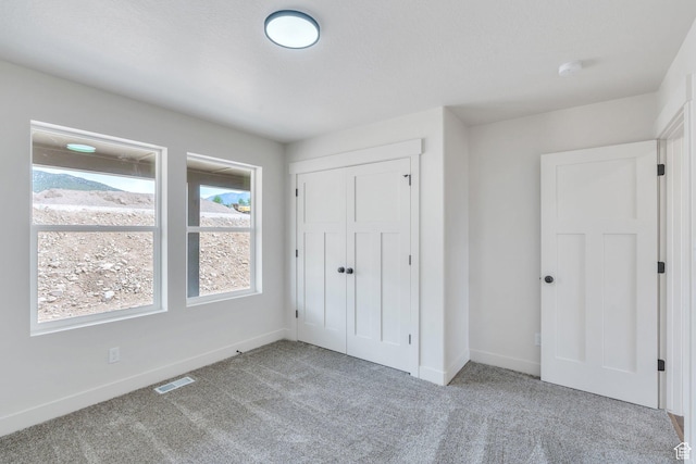 unfurnished bedroom with carpet flooring, baseboards, and a closet