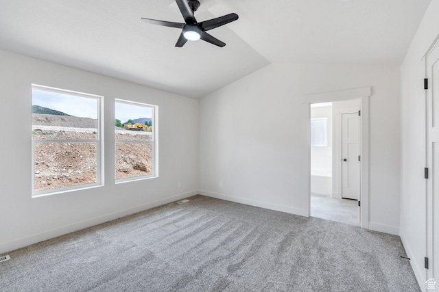 carpeted spare room featuring lofted ceiling, ceiling fan, and baseboards