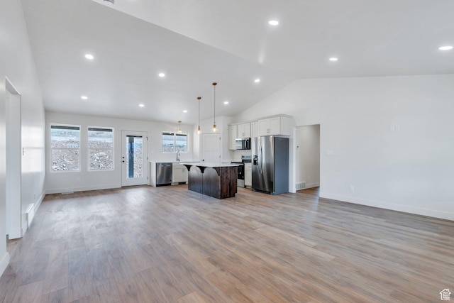 kitchen with stainless steel appliances, open floor plan, a center island, light countertops, and baseboards