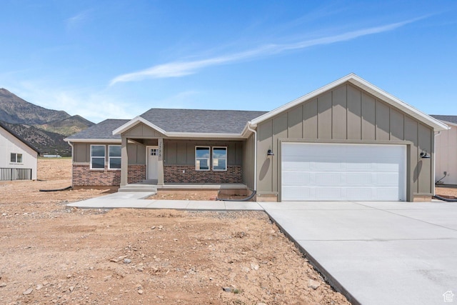 view of front of home with board and batten siding, an attached garage, concrete driveway, a porch, and a mountain view