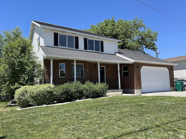 traditional-style house with an attached garage, a porch, a front yard, concrete driveway, and brick siding