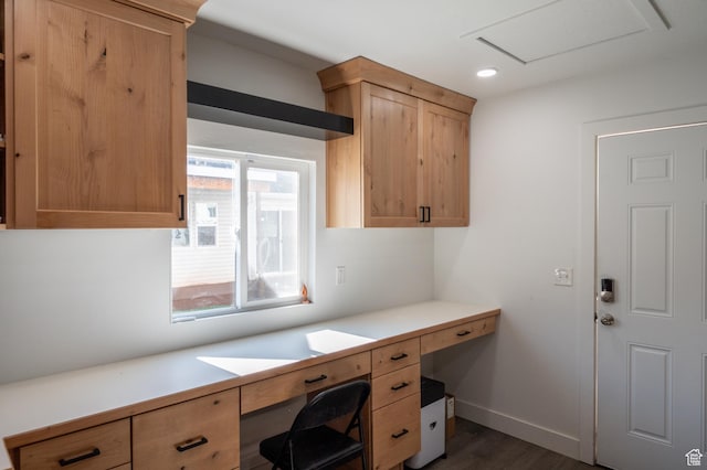 unfurnished office with dark wood-style flooring, baseboards, built in desk, and recessed lighting