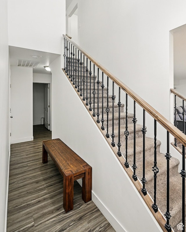 stairway featuring baseboards, wood finished floors, and a towering ceiling