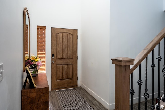 entryway with wood finished floors, baseboards, and stairs