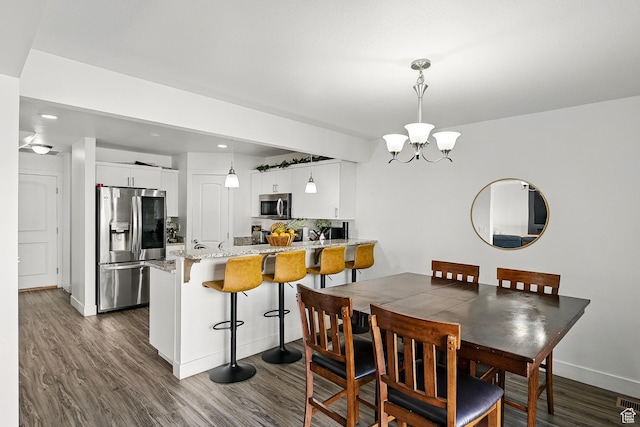 dining space with dark wood-type flooring, a chandelier, baseboards, and recessed lighting