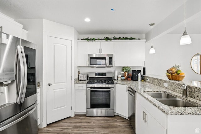 kitchen with stainless steel appliances, a sink, dark wood-type flooring, hanging light fixtures, and recessed lighting