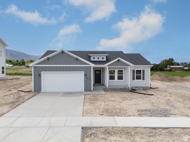 676 E 2450 N, North Logan, UT 84341 - view of front facade featuring board and batten siding, an attached garage, a porch, concrete driveway, and a mountain view
