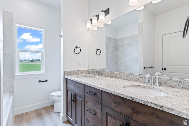 676 E 2450 N, North Logan, UT 84341 - bathroom featuring toilet, baseboards, wood finished floors, and double vanity
