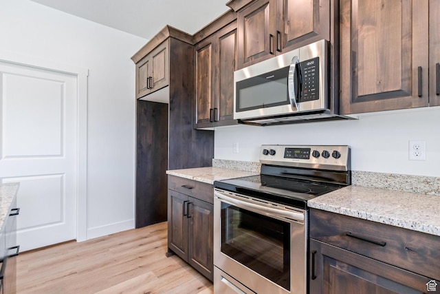 676 E 2450 N, North Logan, UT 84341 - kitchen featuring appliances with stainless steel finishes, dark brown cabinetry, light wood finished floors, and light stone countertops