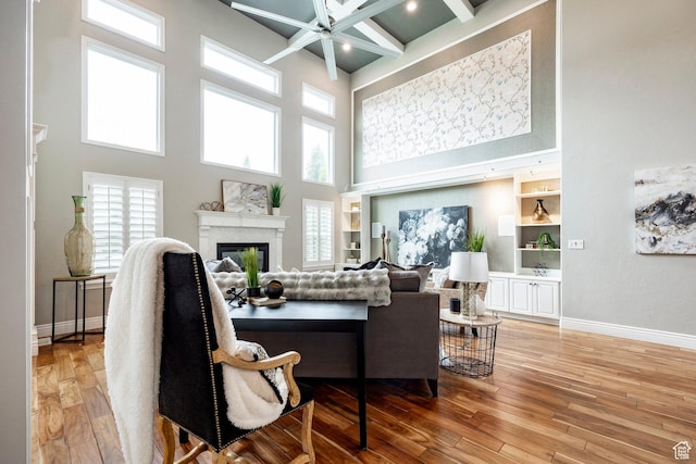1309 W Atrium Ct W, Farmington, UT 84025 - living room featuring a high ceiling, a glass covered fireplace, ceiling fan, light wood-style flooring, and baseboards