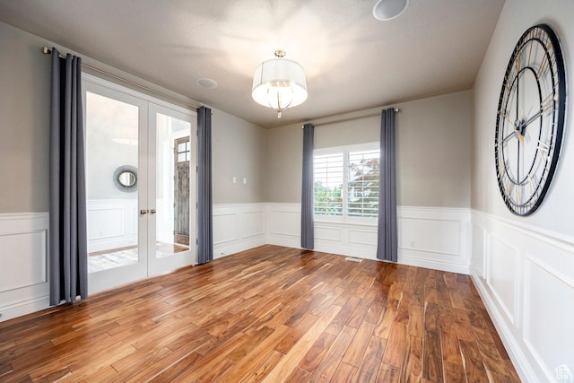 1309 W Atrium Ct W, Farmington, UT 84025 - unfurnished room featuring french doors, wood finished floors, a wainscoted wall, and a decorative wall