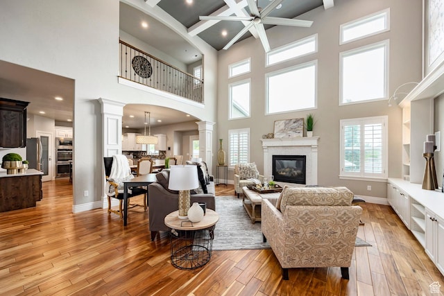 1309 W Atrium Ct W, Farmington, UT 84025 - living room with decorative columns, a high ceiling, light wood-style flooring, a glass covered fireplace, and recessed lighting