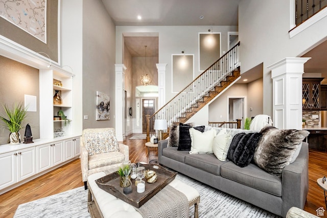 1309 W Atrium Ct W, Farmington, UT 84025 - living area featuring a towering ceiling, light wood finished floors, stairs, ornate columns, and built in features