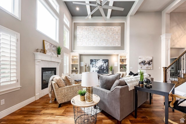 1309 W Atrium Ct W, Farmington, UT 84025 - living room featuring a high ceiling, ceiling fan, stairs, a tiled fireplace, and wood finished floors