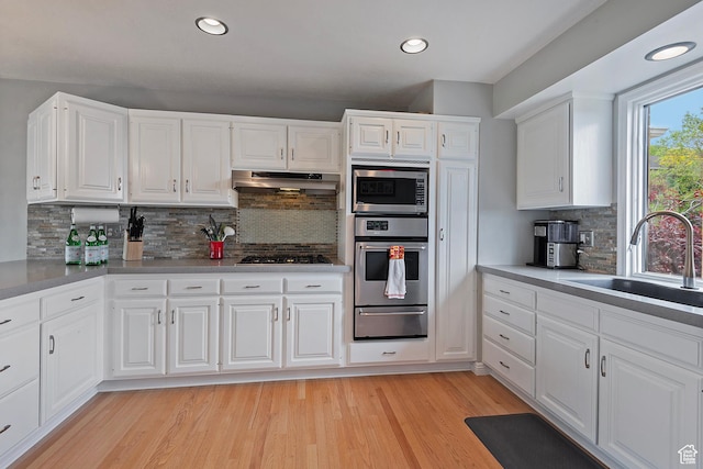 193 Coventry Ln, North Salt Lake, UT 84054 - kitchen featuring appliances with stainless steel finishes, a sink, under cabinet range hood, a warming drawer, and decorative backsplash