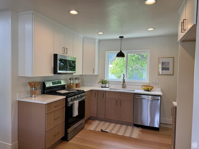 kitchen with stainless steel appliances, a sink, light wood-style flooring, light countertops, and recessed lighting