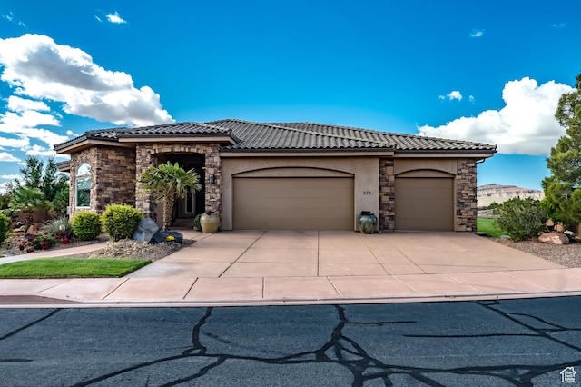 373 W Meridian Dr, Ivins, UT 84738 - view of front of house featuring stone siding, a garage, a tiled roof, and stucco siding