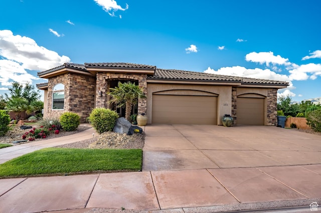 373 W Meridian Dr, Ivins, UT 84738 - mediterranean / spanish-style house with a tile roof, an attached garage, driveway, stucco siding, and stone siding