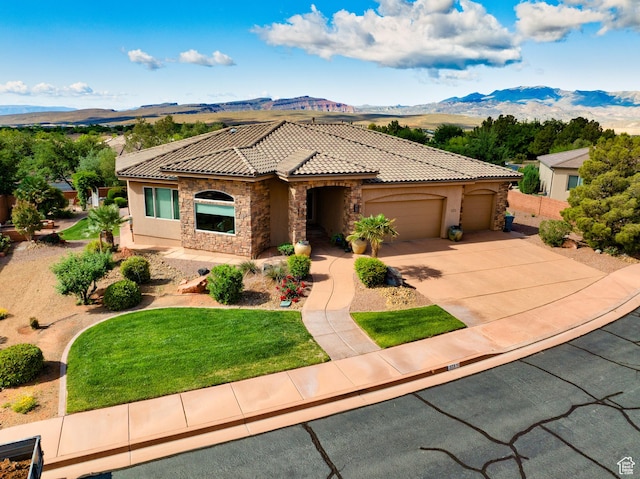 373 W Meridian Dr, Ivins, UT 84738 - mediterranean / spanish-style home featuring a tile roof, a mountain view, stucco siding, a garage, and stone siding